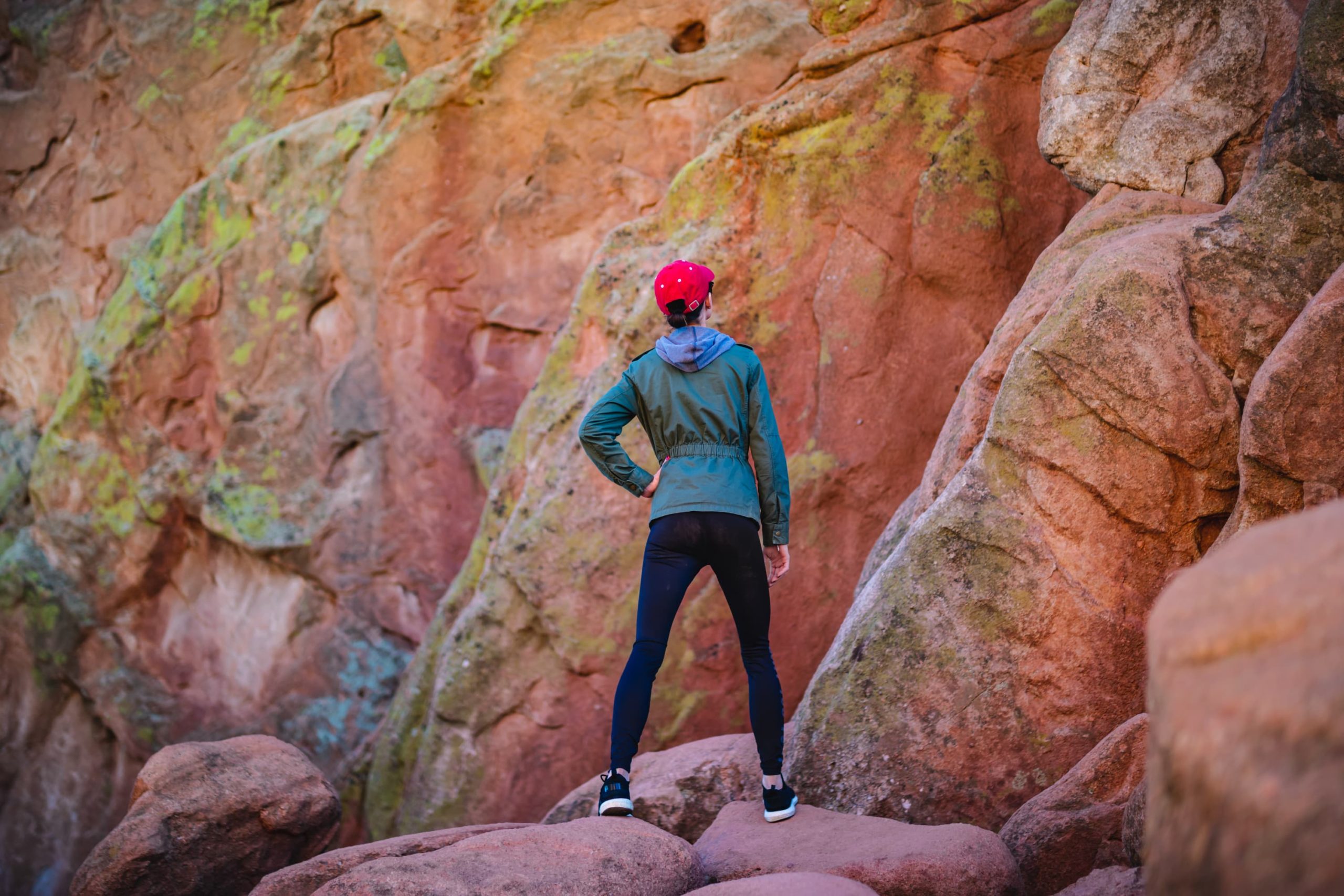 A woman stands on a red rock formation.
