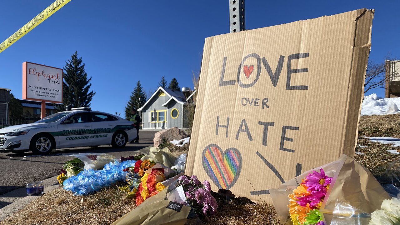 Cardboard Love Over Hate sign surrounded by flowers.